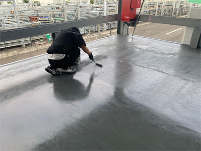 屋外床面に防水材を施工している様子